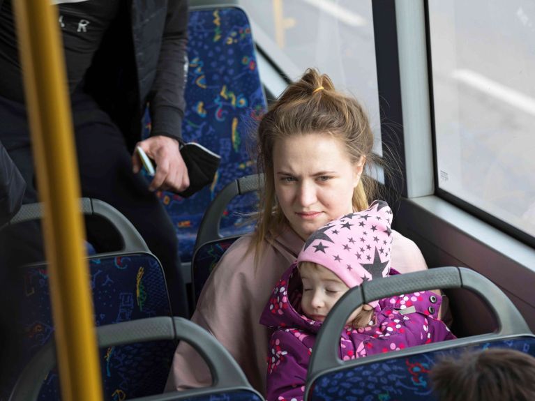 سيدةٌ أوكرانية تنتظرُ مع طفلها في إحدى حافلات برلين للمغادرة إلى مكان إقامتها. 