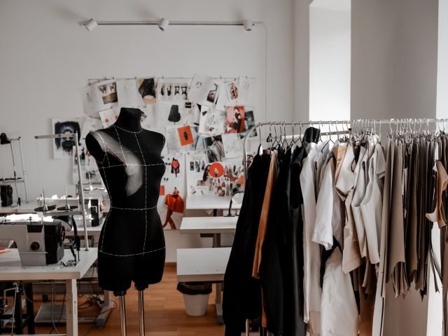 Ein Modeatelier mit Puppe, Kleiderständer und Nähtischen.