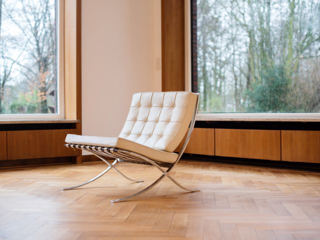 Barcelona-Sessel von Ludwig Mies van der Rohe und Lilly Reich aus dem Jahr 1929 steht in einem Raum mit Parkett und großen Fenstern.