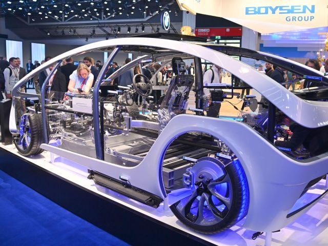 Auf einer Automobilmesse betrachten Besucher ein Auto ohne Karosserie. 