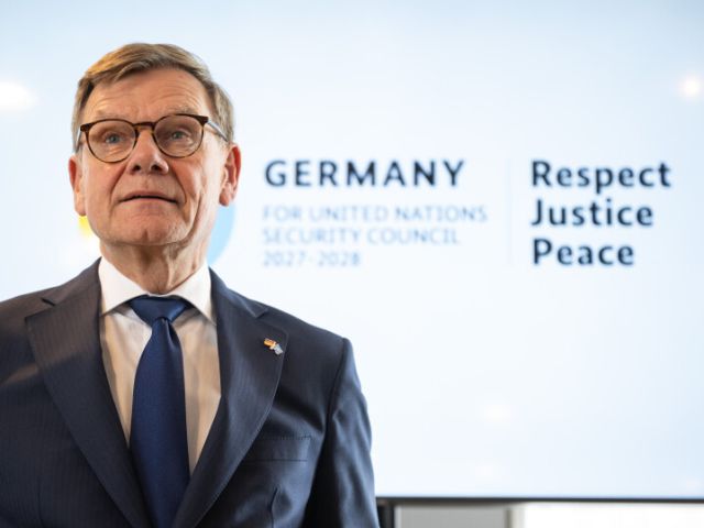 Ein Mann steht vor einer Leinwand, darauf steht „Germany for UN Security Council 2027/2028“.