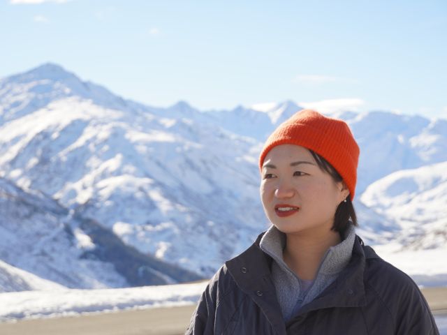 Junge Chinesin vor hohen schneebedeckten Bergen
