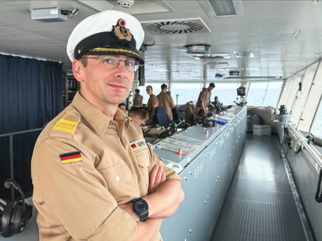 Ein Mann mit Kapitänsmütze und dem Schriftzug „Skipper“ auf dem Hemd blickt in die Kamera. 