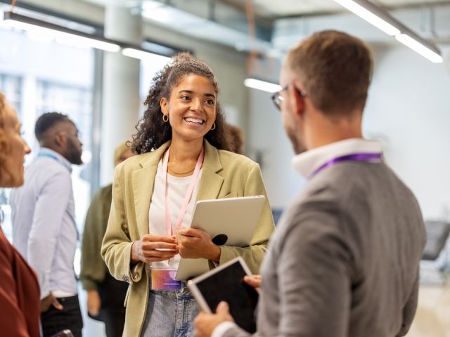 Frau mit Laptop unter dem Arm spricht mit Mann