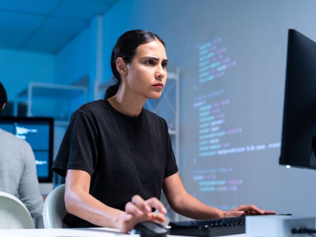 Eine junge Frau betrachtet konzentriert einen Computerbildschirm.