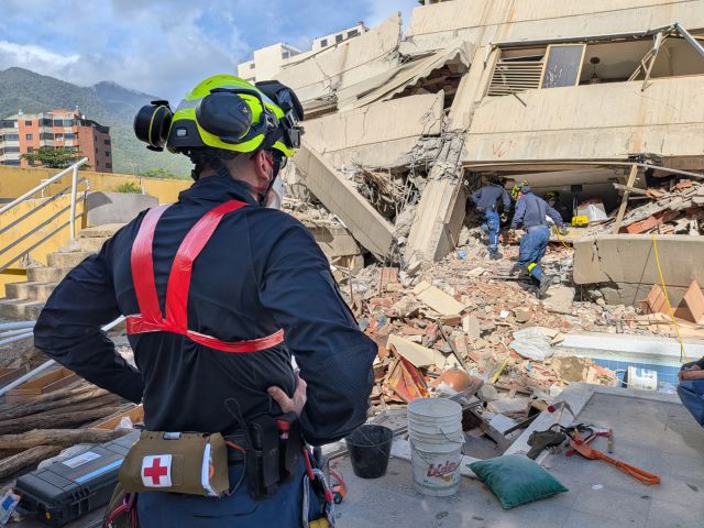 Ein Mann mit Schutzhelm steht vor einem eingestürzten Gebäude