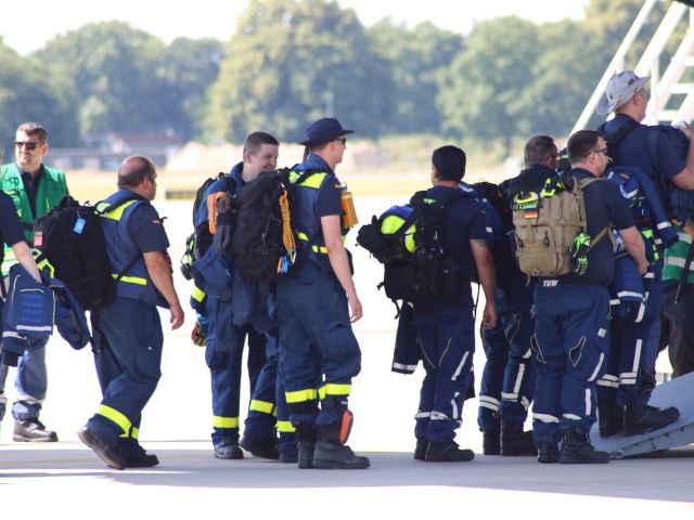 Einsatzkräfte des Technischen Hilfswerks steigen in ein Transportflugzeug.