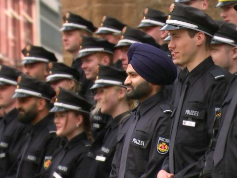 Mehrere junge Männer und Frauen in Polizeiuniform stehen auf  einer Treppe. Einer der Männer trägt einen Turban.