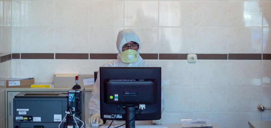 Eine Ärztin im Schutzanzug gibt Daten eines Patienten ein. Eine Ärztin im Schutzanzug gibt Daten eines Patienten ein.