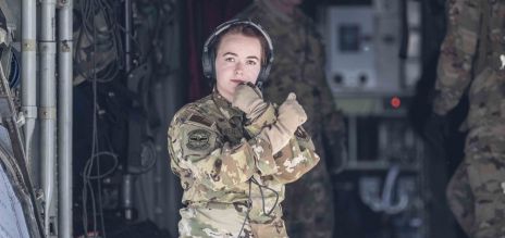 Une soldate se tient dans l’ouverture d’un avion militaire