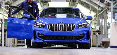 Un empleado de la empresa junto a un BMW Serie 1 azul que sale de la cadena de montaje de la planta de BMW Group en Leipzig.