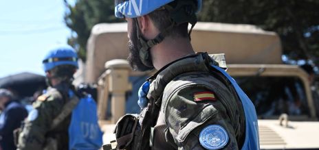 Sur la photo, on aperçoit un soldat de dos. Il porte un gilet bleu arborant l’inscription «&nbsp;UN&nbsp;» et un revêtement bleu sur son casque.
