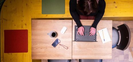 A woman sits at a desk with a laptop. 