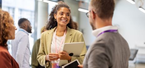 A woman holding a laptop is talking to a man