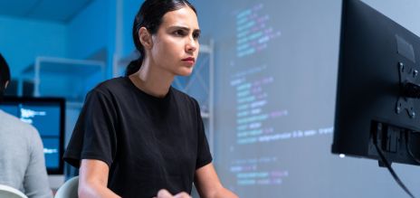 A young woman is looking attentively at a computer screen.