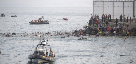 Des personnes nagent dans la mer jusqu’à une falaise