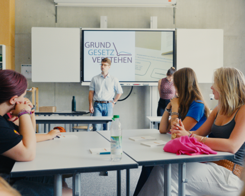 Ein Mann steht vor einer Schulklasse.