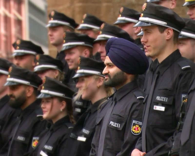 Mehrere junge Männer und Frauen in Polizeiuniform stehen auf  einer Treppe. Einer der Männer trägt einen Turban.