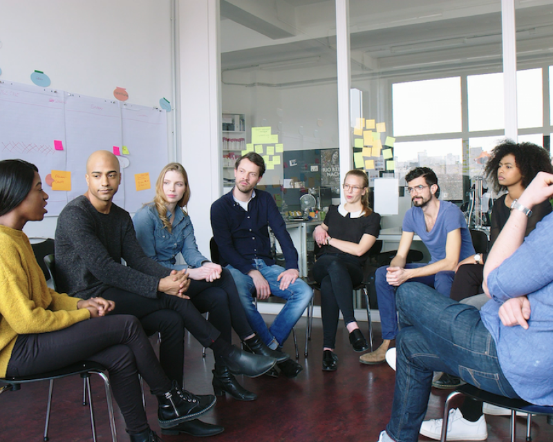 Menschen bilden einen Stuhlkreis.