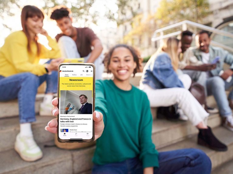 Junge Frau zeigt ein Handy mit einer App