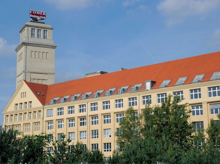 A big yellow building with lots of windows and a red gable roof