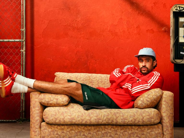 Sänger Bad Bunny in adidas Kleidung auf einer Couch