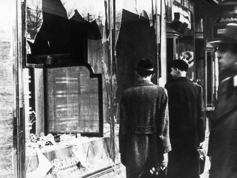 Pogrom sonrası: İnsanlar hasar görmüş dükkanların yanından geçiyor.