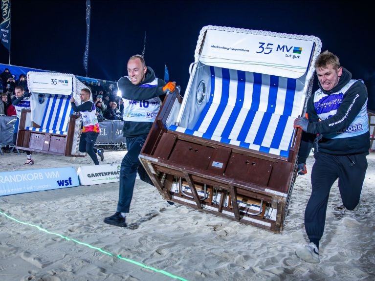 Two men carry a beach chair.