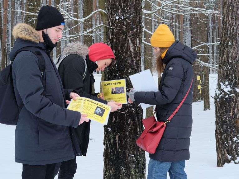 Remembrance volunteers from Austria hang up name signs in the Forest of Names at Blagovshchina. 