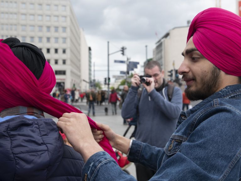 Ein Mann mit einem Turban bindet einer anderen Person einen Turban.