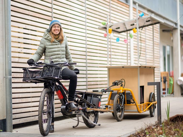 Laura Zöckler ze swoim rowerem transportowym zasilanym energią słoneczną. Ogniwa solarne umieszczone na rowerze umożliwiają naładowanie akumulatora energią słoneczną.