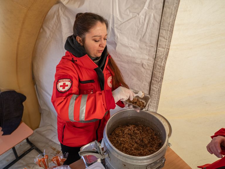 A helper hands out hot meals. 
