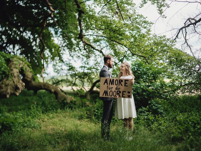 العروسان كورنلسن في حفل زفافهما حاملَين رسالة "Amore für die Moore" (الحبُ للمستنقعات) 