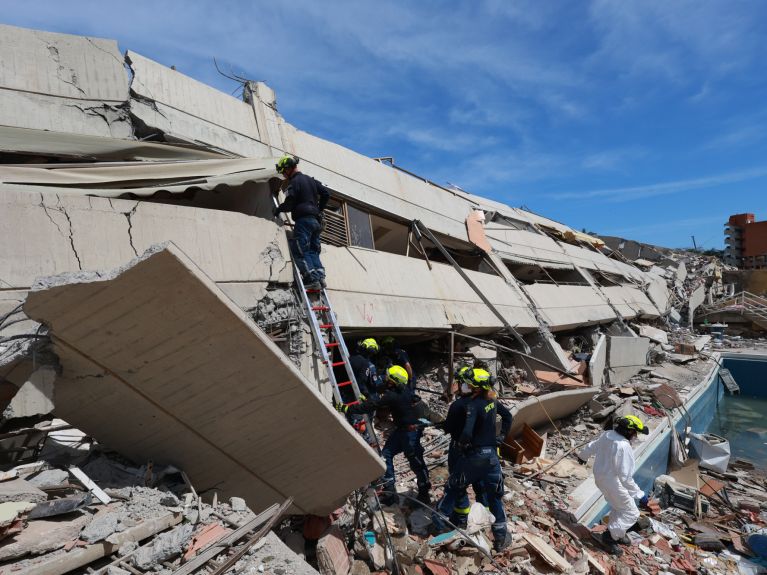 Pessoas com uniforme da THW em um prédio desabado 