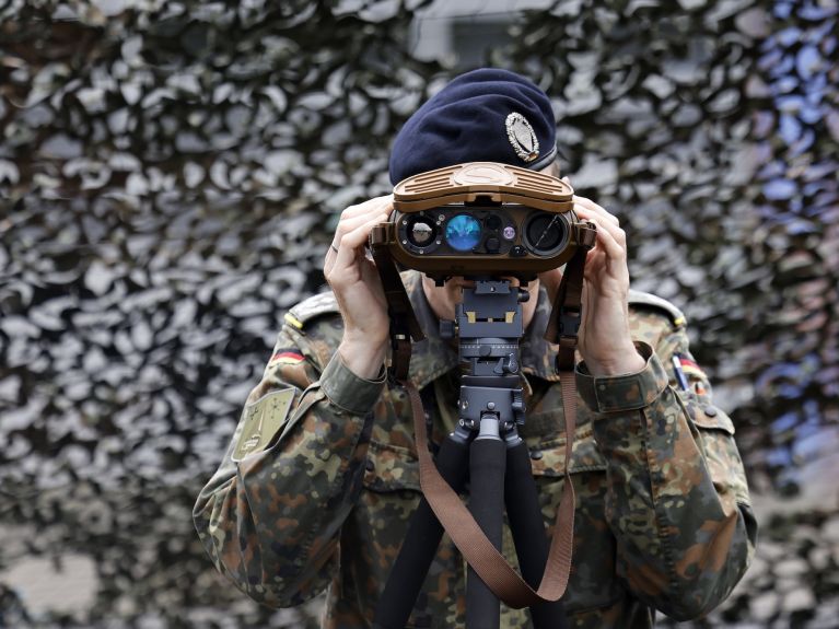 Ein Soldat der Bundeswehr blickt durch ein Fernglas. 