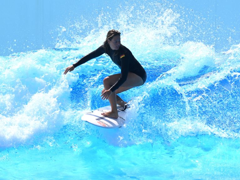 Frau surft auf künstlicher Welle
