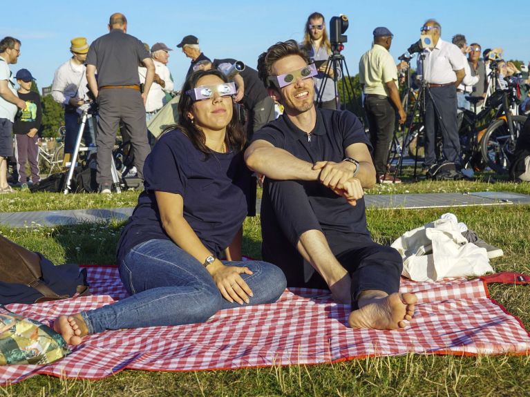 Mit selbstgebauten Brillen beobachten Menschen die Sonnenfinsternis.