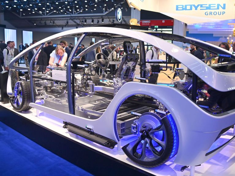 Auf einer Automobilmesse betrachten Besucher ein Auto ohne Karosserie. Auf einer Automobilmesse betrachten Besucher ein Auto ohne Karosserie.
