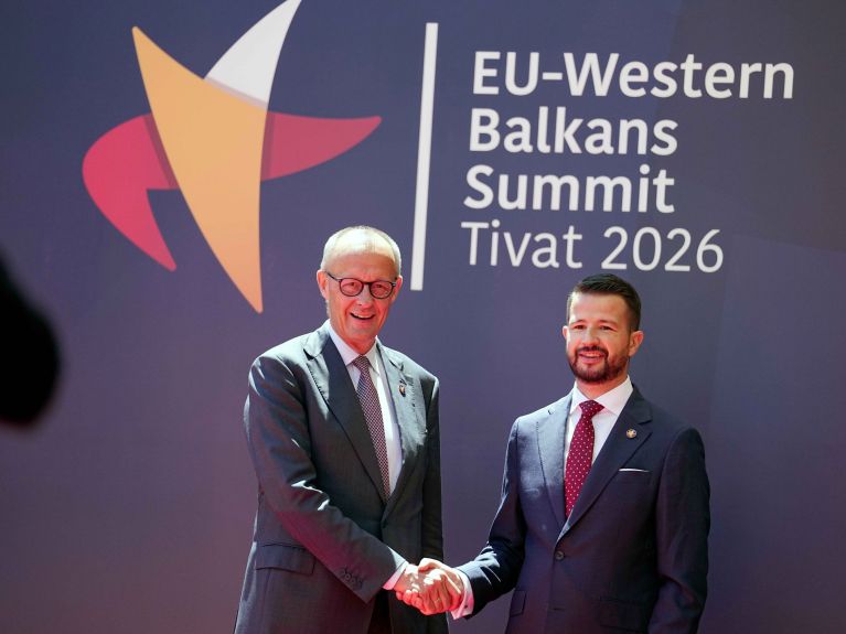 El canciller alemán, Friedrich Merz, estrecha la mano del presidente de Montenegro, Jakov Milatovic. Los dos dirigentes posan ante un cartel con la inscripción “EU Western Balkans Summit Tivat 2026”. 