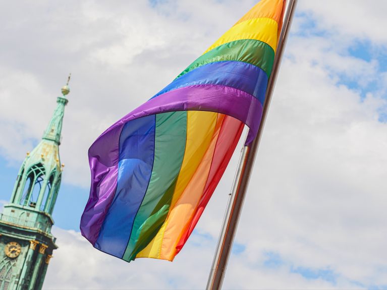 Regenbogenfahnen wehen vor der Kirchturmspitze der Sankt Marienkirche im Berliner Bezirk Mitte