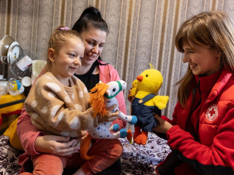 A Ukrainian Red Cross helper with a woman and her daughter in an emergency shelter in Terebovlia in western Ukraine. 
