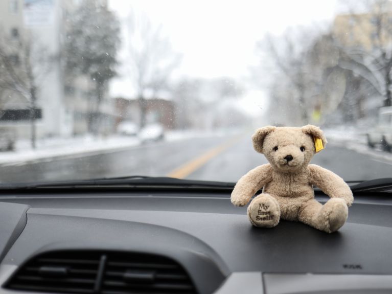 Teddybär sitz auf einem Amaturenbrett eines Autos