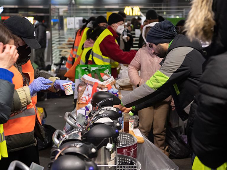 Refugees who have arrived from Ukraine are given warm drinks and something to eat at a counter after their arrival at Berlin Central Station.