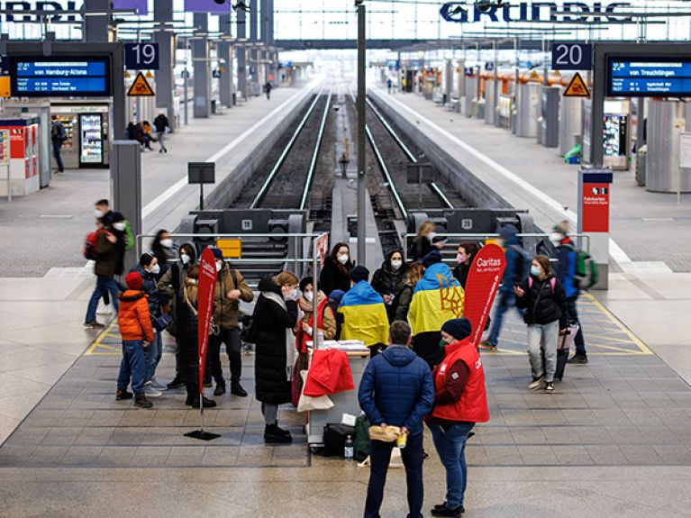 Helpers work with refugee Ukrainians at an information point at Munich Central Station.