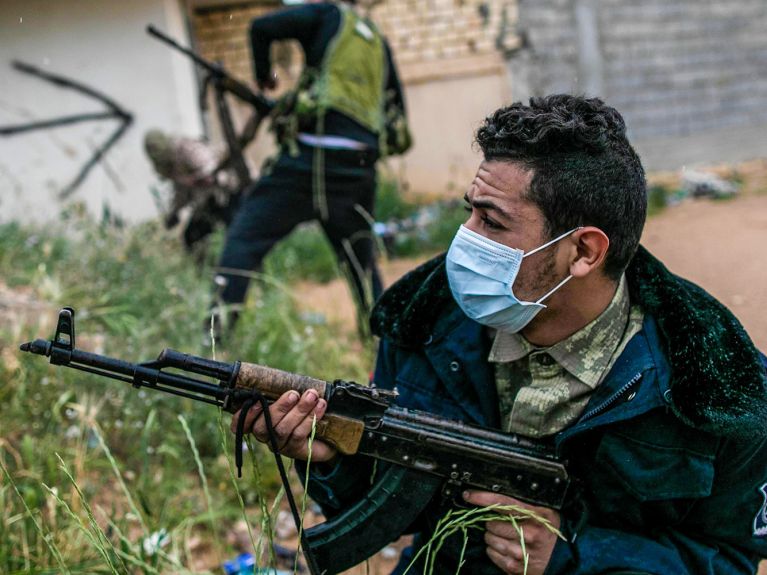 Libye : des combattants armés portant un masque de protection sur le nez et la bouche