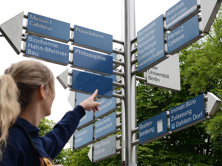 Studentin vor Hinweisschild an Universität Studentin vor Hinweisschild an Universität