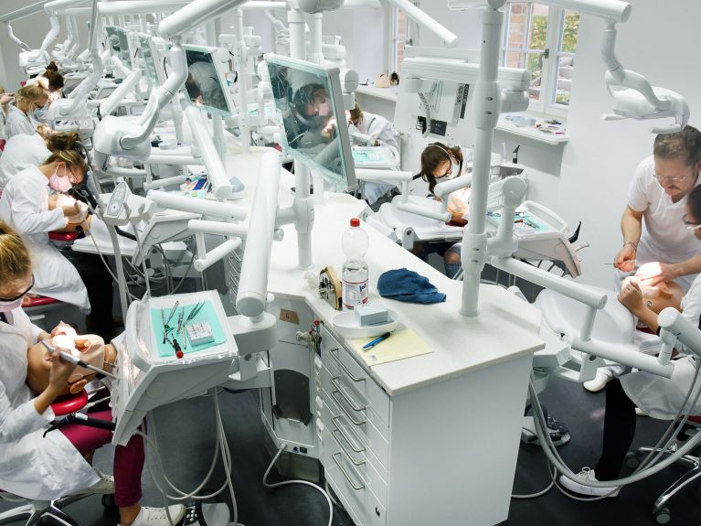 Praticando em uma cabeça-modelo. Futuros dentistas durante o estudo.