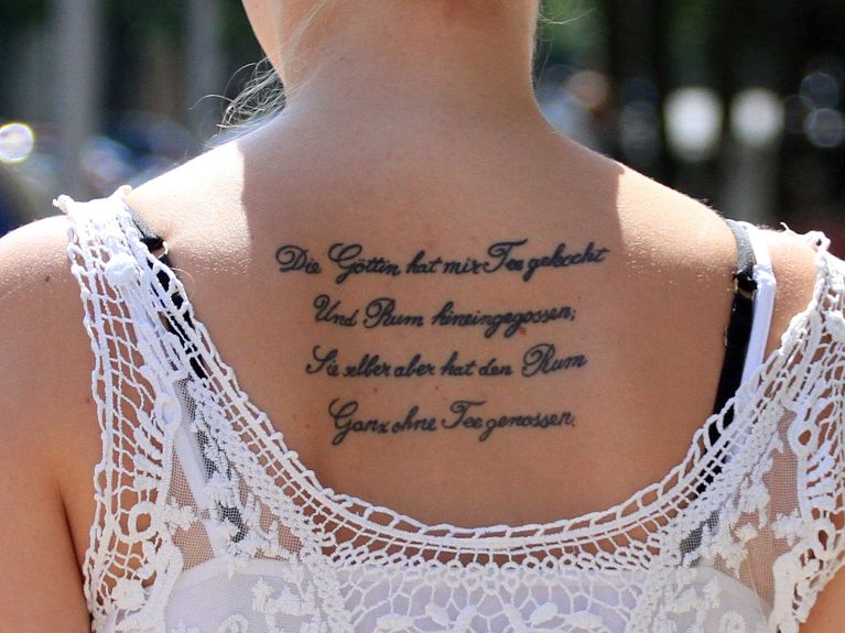 Молодая женщина с татуировкой в виде стихотворения Генриха Гейне
