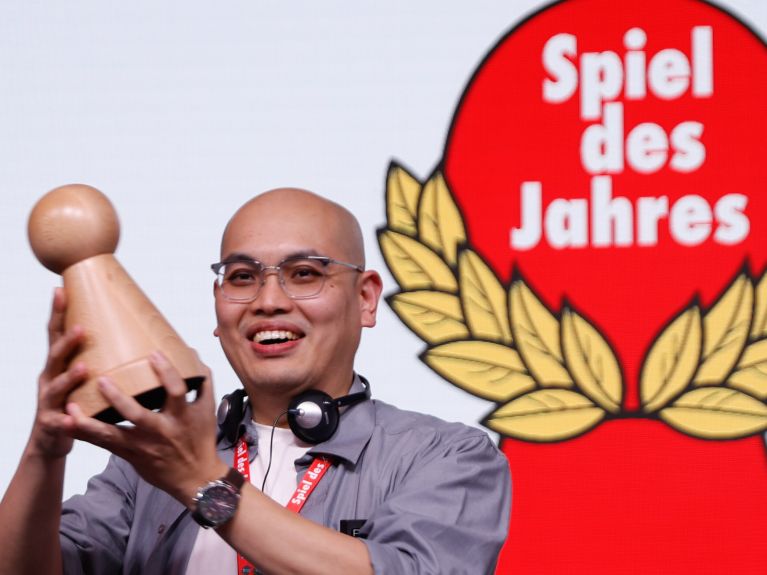 Mann hält große Spielfigur in der Hand