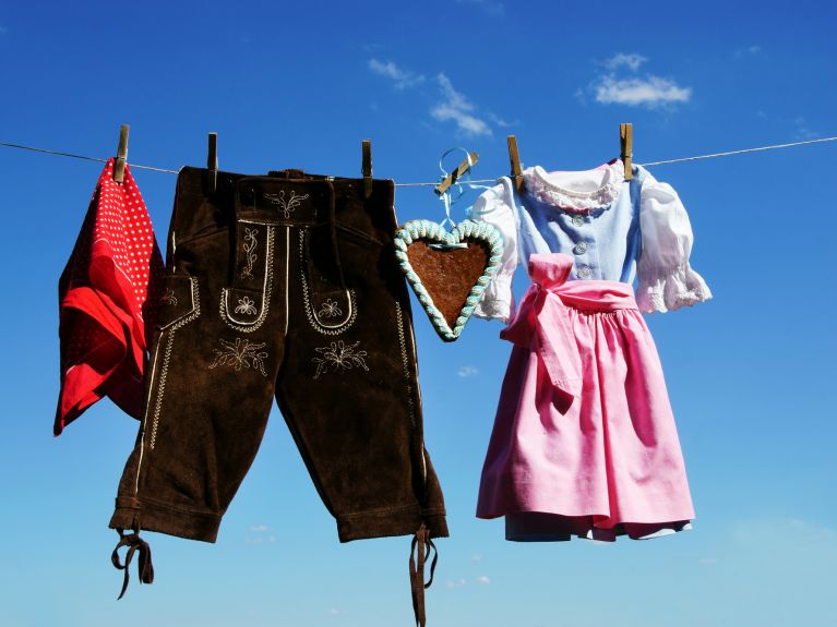 Tradición bávara tendida al sol: lederhose y dirndl bajo un cielo blanco y azul